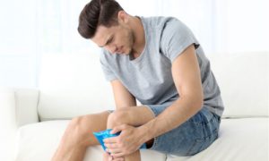 The man applies a cold compress to his injured leg.