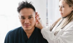 A man receives an acupuncture through the ear pressure points.